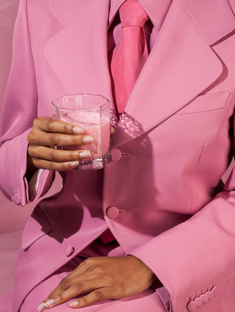 Person wearing a pink suit holding a drink, symbolizing confidence and relaxed success