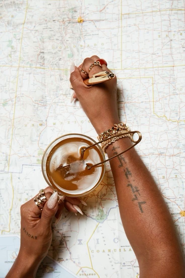 Woman writing notes on a map at a desk adorned with coffee and gold accents, representing planning, reflection, and intentional journeys.