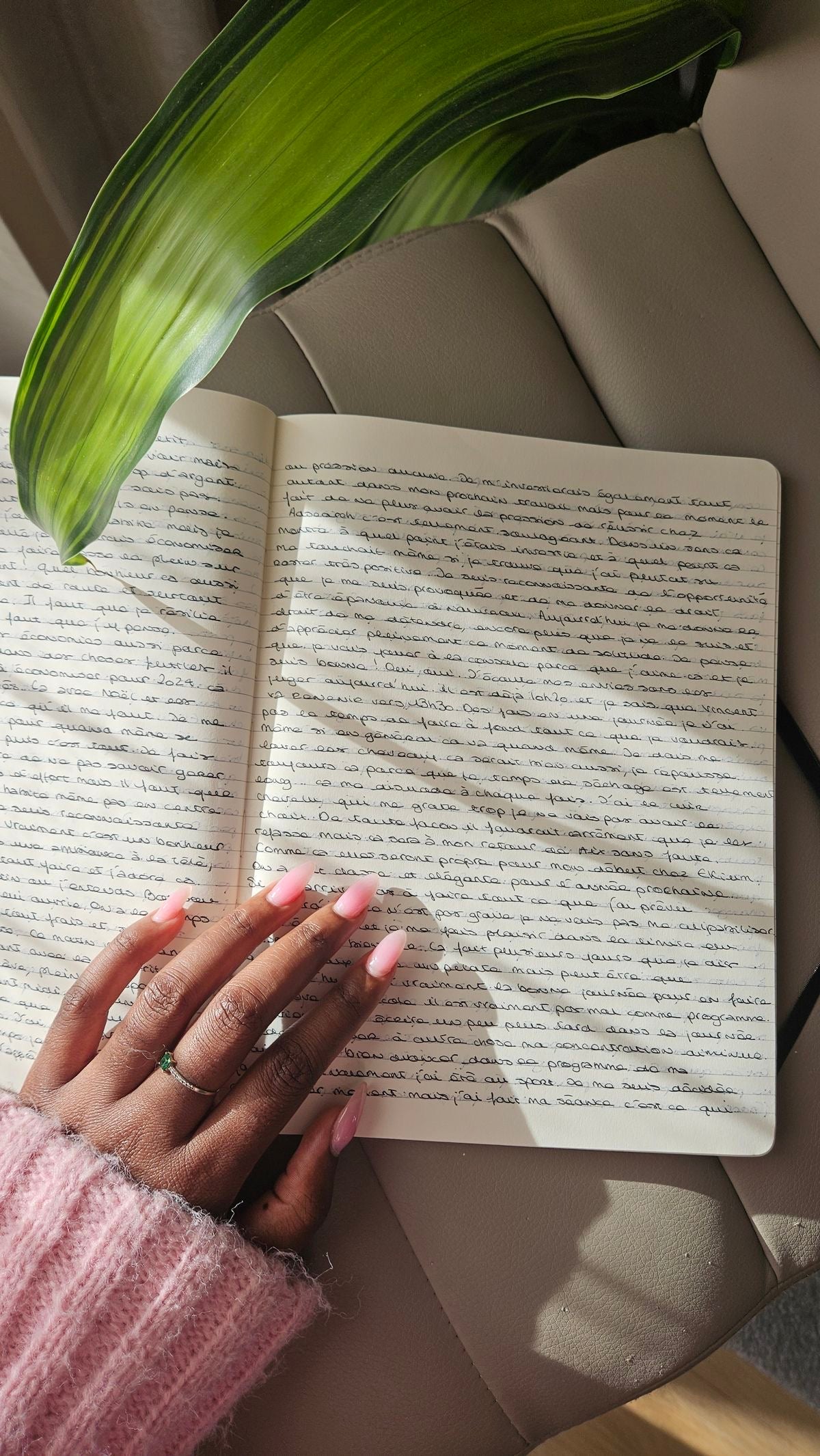 Open book with a hand on a surface, next to a plant