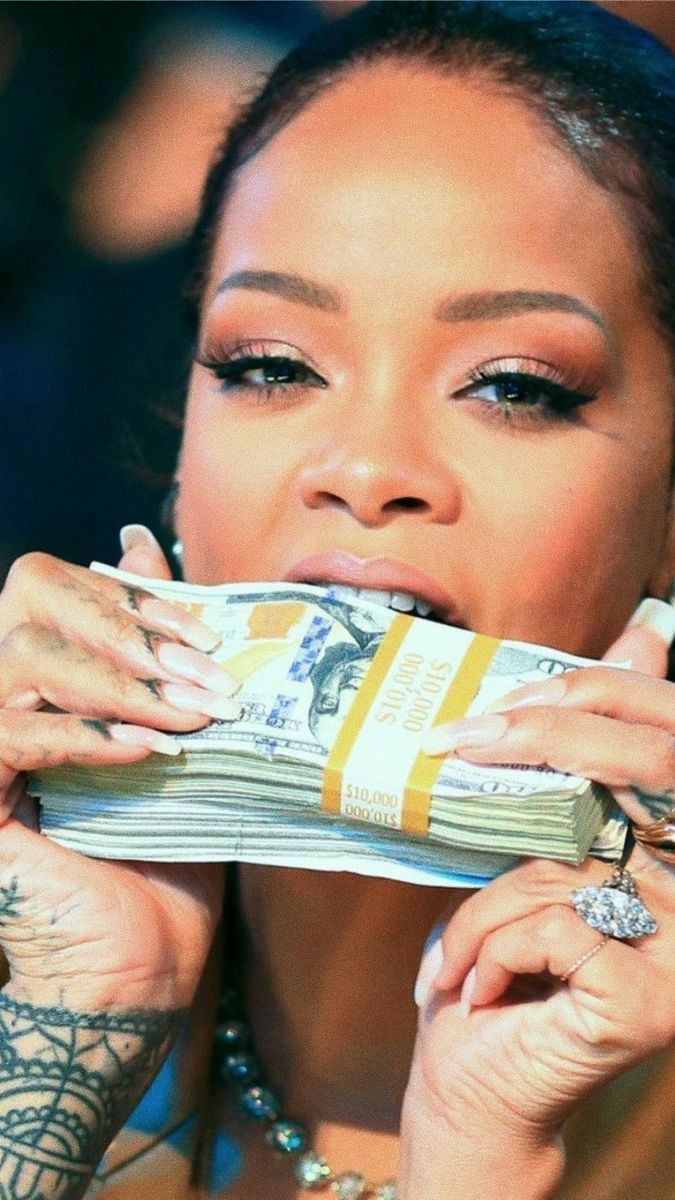 Rihanna biting a stack of cash with a bold, confident expression symbolizing wealth and power