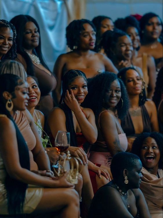 Black woman smiling at networking event, holding coffee in one hand