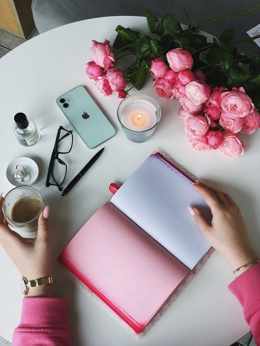 Woman sitting at a table with a journal, deep in thought, symbolizing self-reflection, healing, and emotional clarity through writing.